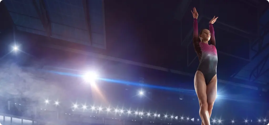 A gymnast balances gracefully on a beam in a large, brightly lit arena. She wears a sparkling leotard, with spotlights highlighting her poised form.