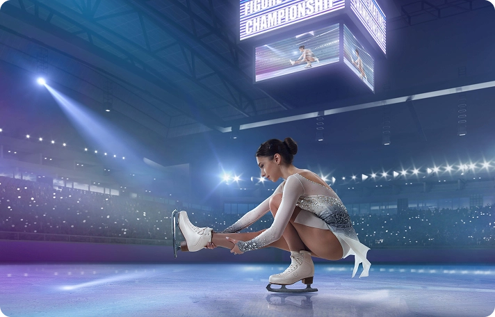 A figure skater in a sparkling outfit ties her ice skate on a brightly lit rink. The arena is filled with spectators, and a "Championship" sign hangs above.